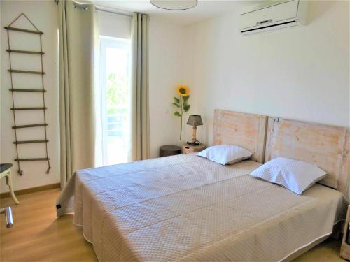 a bedroom with a bed and a window with a ladder at Apartamento Girassol Cabanas Gardens by Your Home Algarve in Cabanas de Tavira