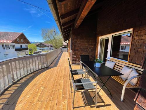 a deck with a black table and chairs on a house at Hirschbachwinkel - fewo-badhindelang in Bad Hindelang