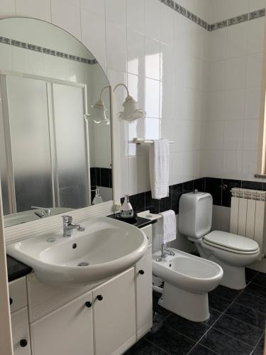 La salle de bains blanche est pourvue d'un lavabo et de toilettes. dans l'établissement Casa Vacanze Ileana, à Patti