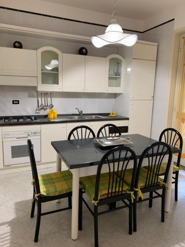 una cucina con tavolo e sedie e una cucina con armadietti bianchi di Casa Vacanze Ileana a Patti