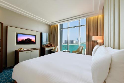 a hotel room with a large bed and a large window at Grand Swiss-Belhotel Waterfront Seef in Manama