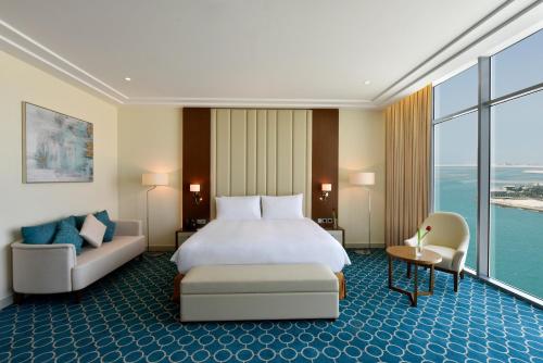 Grand Swiss-Belhotel Waterfront Seef في المنامة: غرفه فندقيه بسرير واريكه
