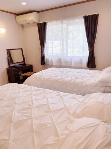 a large white bed in a bedroom with a window at Young House in Matsudo