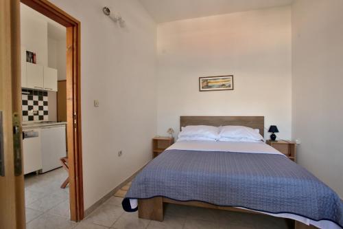 ein Schlafzimmer mit einem Bett mit einer blauen Decke in der Unterkunft Apartman Branko in Pag