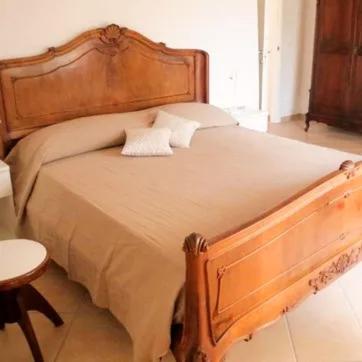 a bedroom with a large bed with a wooden headboard at Finale Ligure Gorra Rooms Rosa di Mare vicino al mare lontano dal caos! in Borgio Verezzi