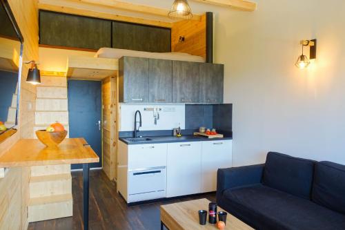 eine Küche mit weißen Schränken und einem Sofa in einem Zimmer in der Unterkunft Studio LUMINEUX à 5 minutes du lac de Serre Ponçon in Prunières