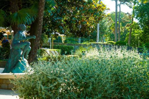 a statue of a woman sitting in a garden at Hotel Marko in Portorož