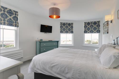 a bedroom with a white bed and two windows at Master accommodation suite 7 sea view in Hastings
