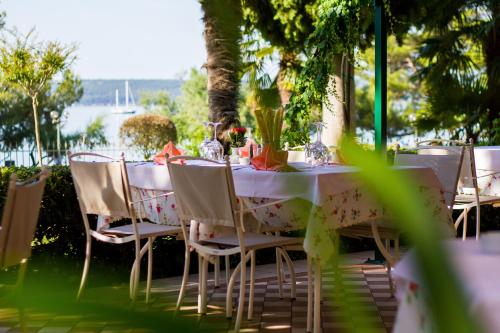 a table with white chairs and a table with flowers on it at Hotel Marko in Portorož