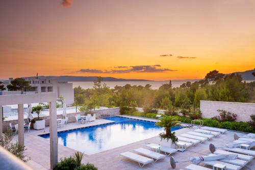 uma piscina com espreguiçadeiras e um pôr-do-sol ao fundo em Poseidon Mobile Home Resort em Makarska