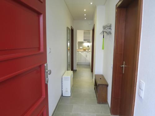 a hallway with a red door and a hallway with a room at Ferienwohnungen Haus Hinneres in Schalkenmehren