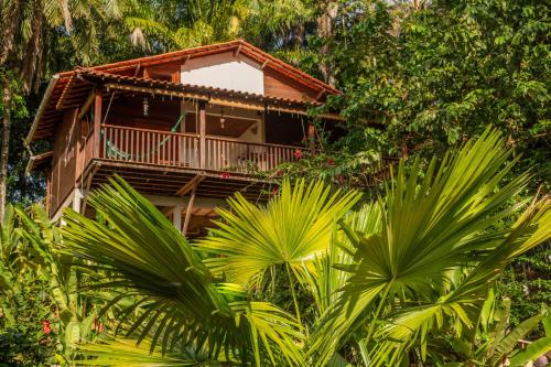 a building with a balcony in the middle of trees at Pousada Horizonte Azul in Ilha de Boipeba