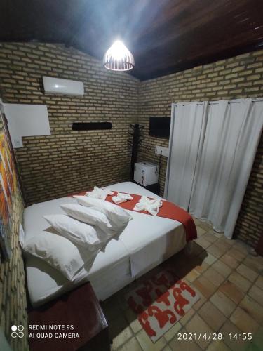 a bedroom with a bed in a brick wall at Chalé 17 - Porto do Sol - Pipa in Pipa