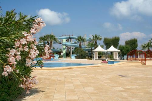 a swimming pool with a resort in the background at Happy Camp mobile homes in Camping Villaggio Lamaforca in Carovigno