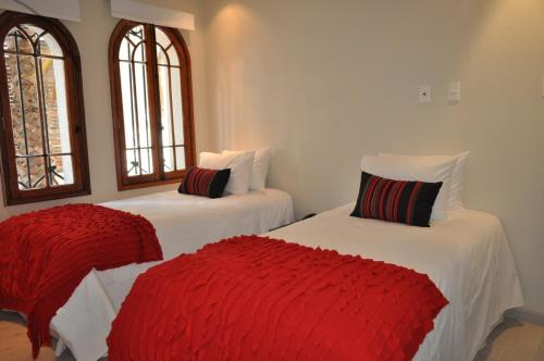 two beds in a room with red and white sheets at Hotel CasaDeTodos in Santiago