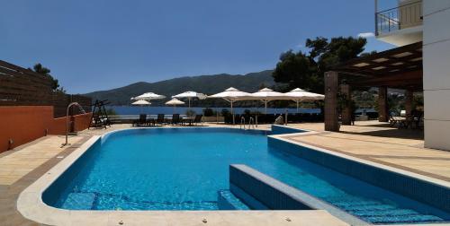a swimming pool with tables and umbrellas on a resort at Golden View in Poros
