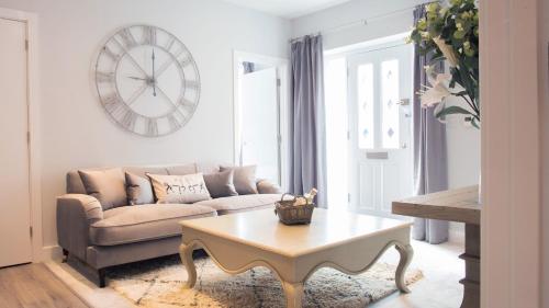 a living room with a couch and a table and a clock at Modern Apartment in Stratford upon Avon with Parking WIFI and Netflix in Stratford-upon-Avon