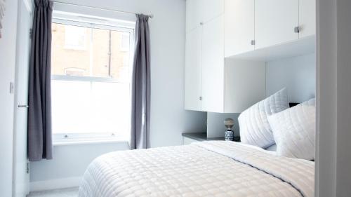 een witte slaapkamer met een bed en een raam bij Modern Apartment with FREE Parking, WIFI and Netflix in Stratford-upon-Avon