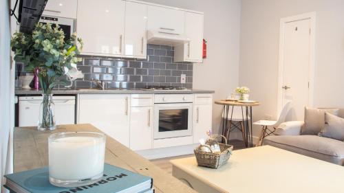 a kitchen with white cabinets and a table with a glass of milk at Modern Apartment in Stratford upon Avon with Parking WIFI and Netflix in Stratford-upon-Avon
