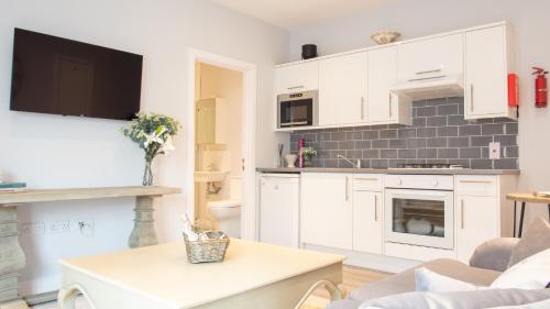 a kitchen with white cabinets and a table in a room at Modern Apartment in Stratford upon Avon with Parking WIFI and Netflix in Stratford-upon-Avon