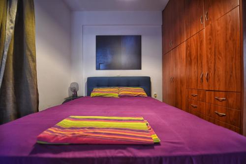 a bedroom with a bed with a purple blanket on it at Maisonette Ilios in Plisioí