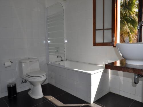 a white bathroom with a toilet and a sink at Hotel CasaDeTodos in Santiago