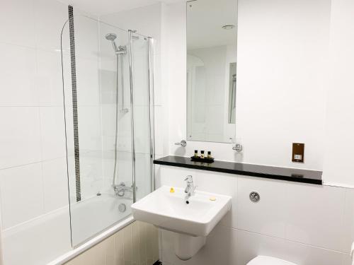 a white bathroom with a sink and a shower at Cotels at The HUB Serviced Apartments, Superfast Broadband, Central Location, Free Parking in Milton Keynes