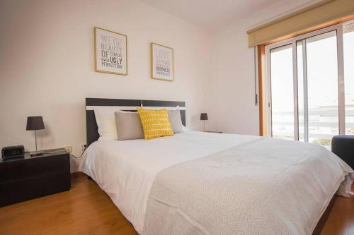 a bedroom with a large white bed with yellow pillows at CASA DA ELSA- ESTACIONAMENTO PRIVADO GRATUITO in Gafanha da Nazaré