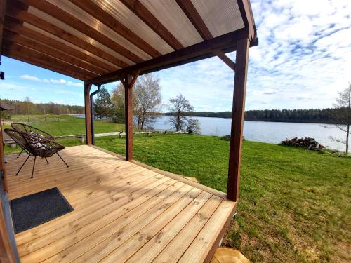 a wooden deck with a bench and a view of a lake at Siesarties Namukas in Mindūnai
