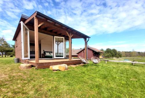 a small cabin with a porch on a grass field at Siesarties Namukas in Mindūnai