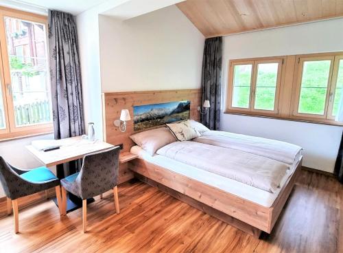 een slaapkamer met een bed, een bureau en ramen bij Triftblick in Gadmen