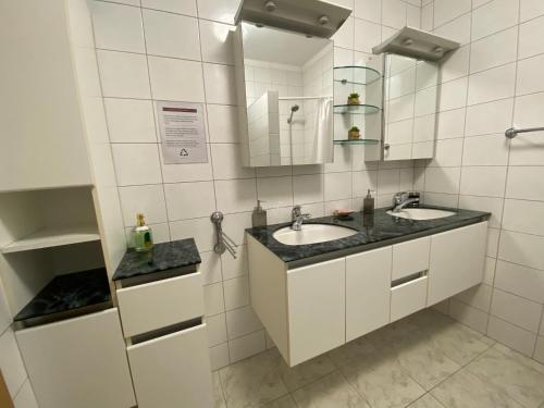 ein weiß gefliestes Bad mit 2 Waschbecken und einem Spiegel in der Unterkunft Villa Janja in Šilo