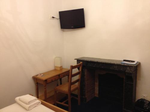 a room with a desk and a tv on the wall at Hotel Couleurs Sud Centre-ville Gare Charleville-Mézières in Charleville-Mézières