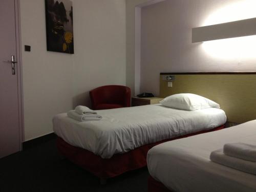 a hotel room with two beds and a red chair at Hotel Couleurs Sud Centre-ville Gare Charleville-Mézières in Charleville-Mézières
