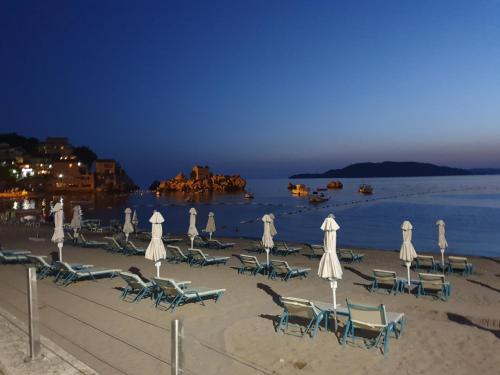 a group of chairs and umbrellas on a beach at night at Apartman Azzuro in Pržno