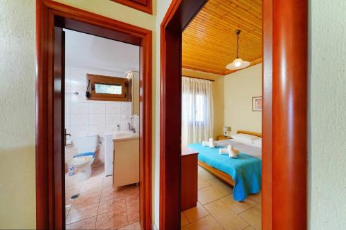 Klisma Beach House في سكالا كاليراخيس: غرفة نوم مع سرير وحمام مع حوض استحمام