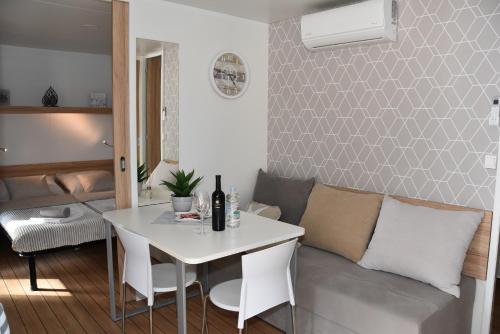 a living room with a white table and a couch at Mobile Home Starfish I Camp Soline in Biograd na Moru