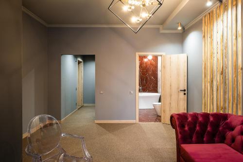 RICH Boutique-Hotel في فينيتسا: غرفة معيشة مع أريكة حمراء وحمام