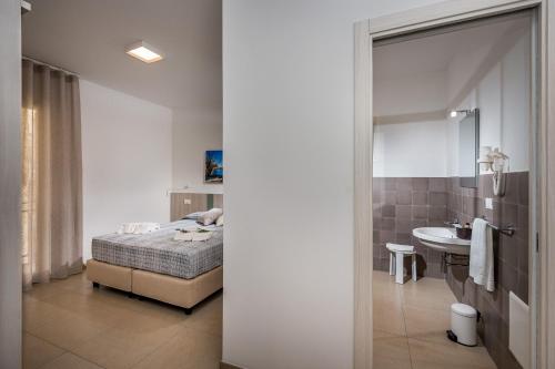 ein Schlafzimmer mit einem Bett und ein Badezimmer mit einem Waschbecken in der Unterkunft Affittacamere Nanà in Castellammare del Golfo