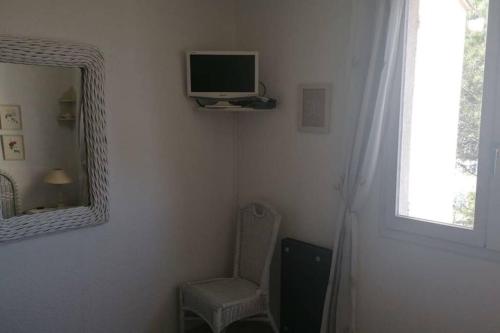 een kamer met een tv, een stoel en een spiegel bij Appartement très agréable in Fréjus