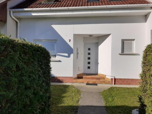 una casa blanca con una puerta y un patio en Csilla Haus, en Bük