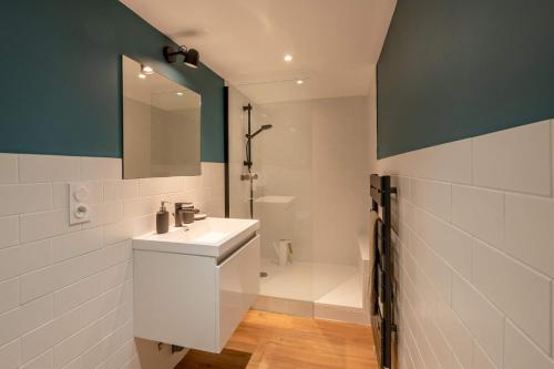 La salle de bains est pourvue d'un lavabo blanc et d'une douche. dans l'établissement Maloca' Robretières, à La Roche-sur-Yon