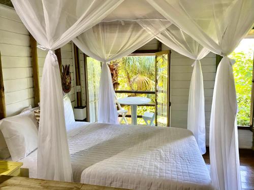 a bedroom with a white bed with a canopy at Pousada Bungalow in Praia do Rosa