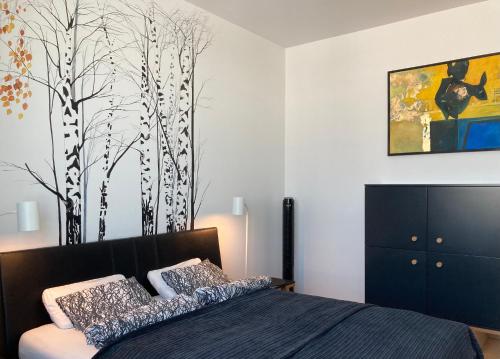 1 dormitorio con 1 cama y un mural de árboles en Baltiq Plaza Apartment, en Gdynia