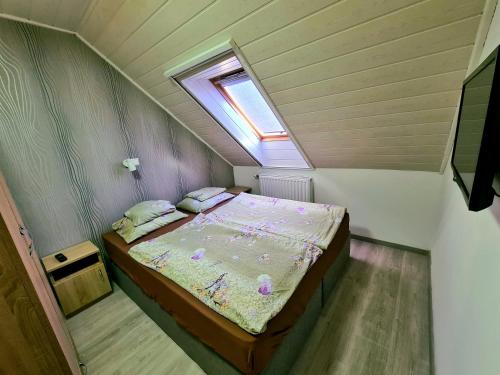 um pequeno quarto com uma cama no sótão em Regina Apartman Hegykő em Hegykő