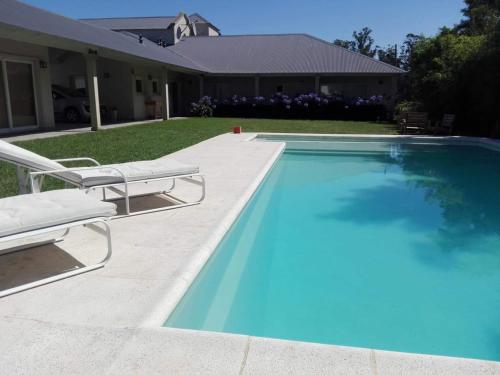 a swimming pool with two lounge chairs next to a house at Villa Clarita Tandil in Tandil