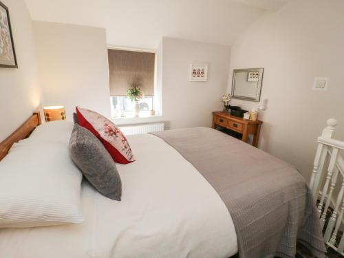 1 dormitorio con cama blanca y almohadas rojas en Marlin Cottage en Conwy