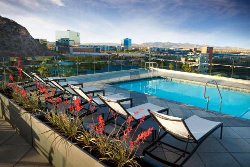 uma piscina no telhado de um edifício com cadeiras e flores em Hyatt Place Tempe Phoenix University em Tempe