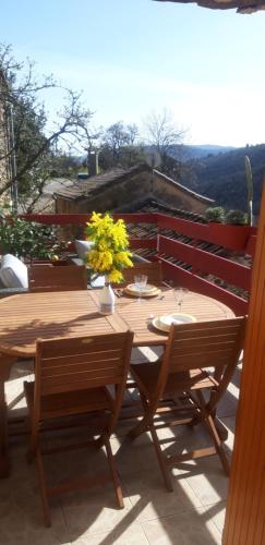 a wooden table with chairs and flowers on a patio at Gîtes chez Daniel "Cevennes 2" in Mars