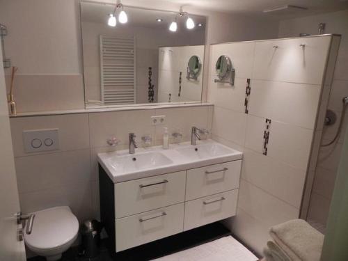 ein Badezimmer mit einem Waschbecken, einem WC und einem Spiegel in der Unterkunft Ferienwohnung Stryck in Tettnang
